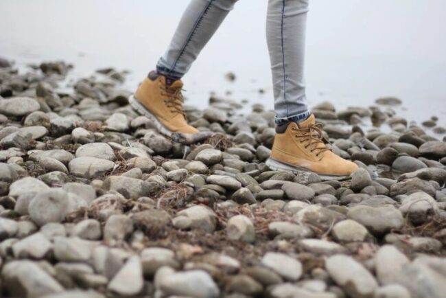 Person wearing tan boots walking on rocky terrain.